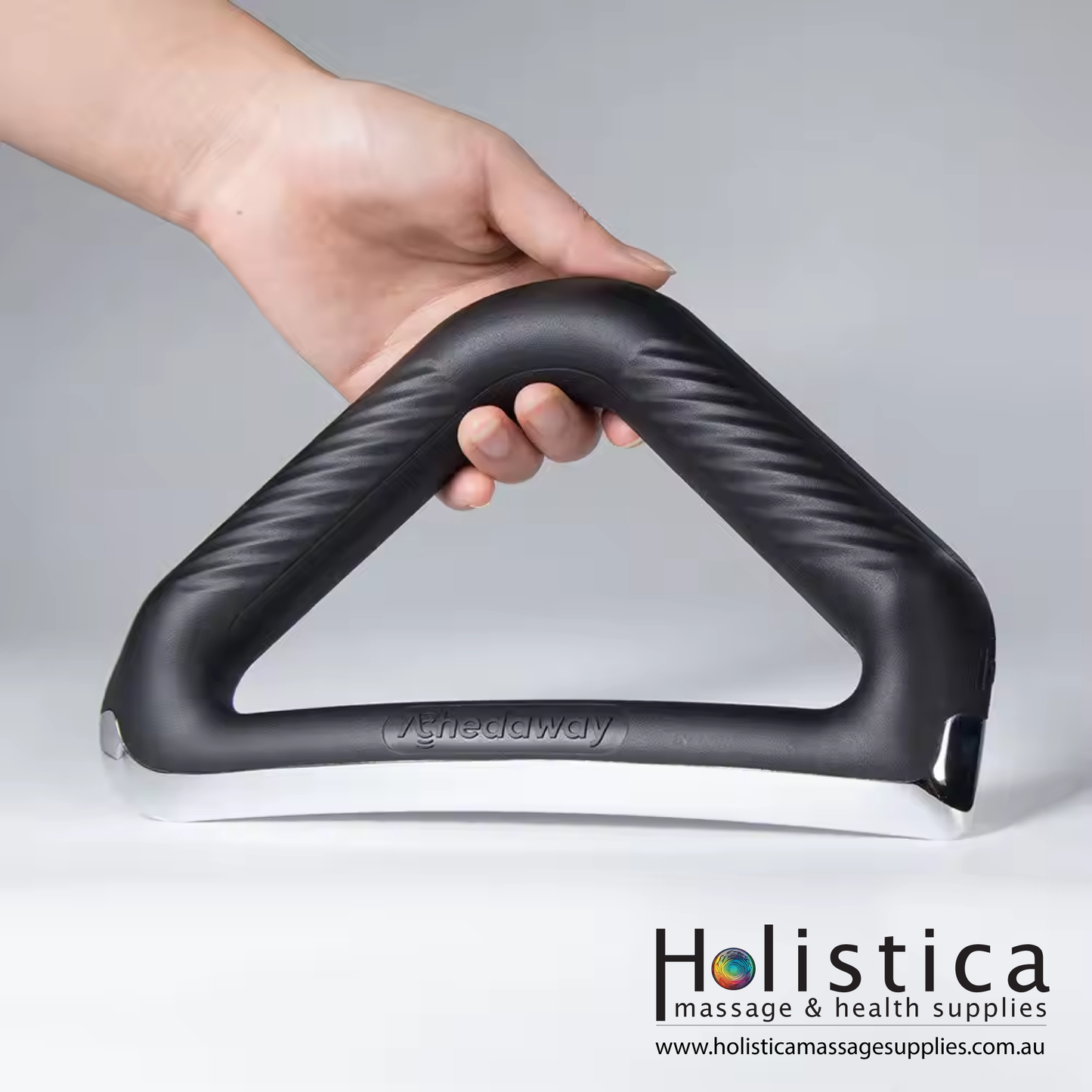 A hand holding a heated electrical scraper, used by a massage therapist for muscle therapy.